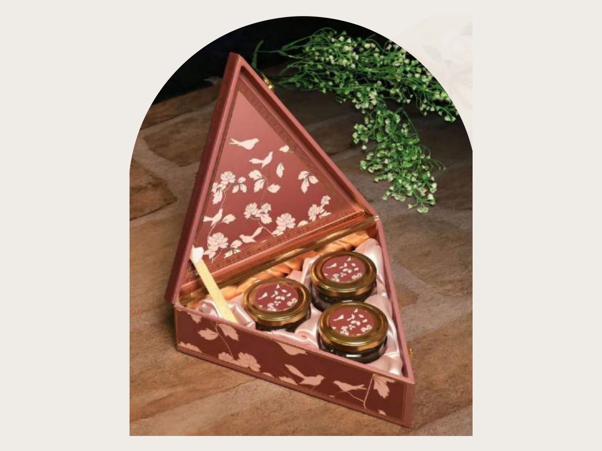 Triangular wooden gift hamper, open, with three jars on a satin lining